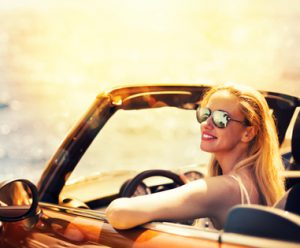 Young Caucasian woman in cabriolet car near sea